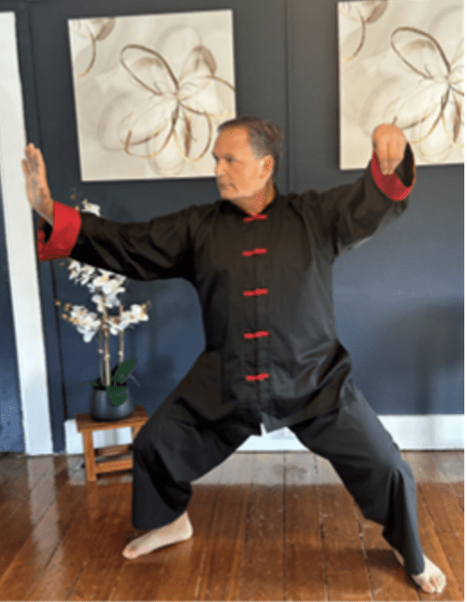 A man practicing Tai Chi in traditional attire indoors.