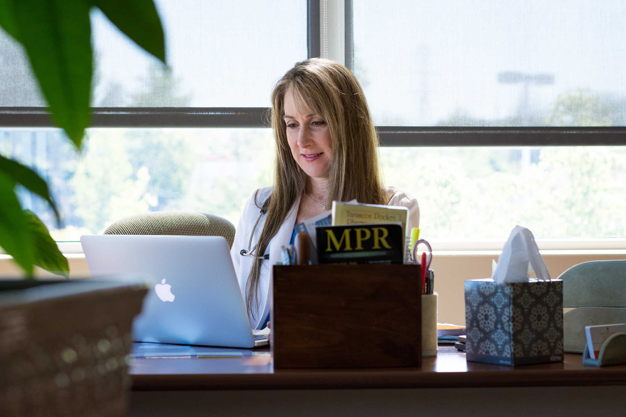 A woman working on a laptop at a desk with an MPR coffee mug.