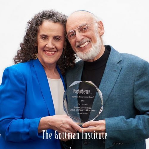 A happy couple holding a glass award from The Goldman Institute.