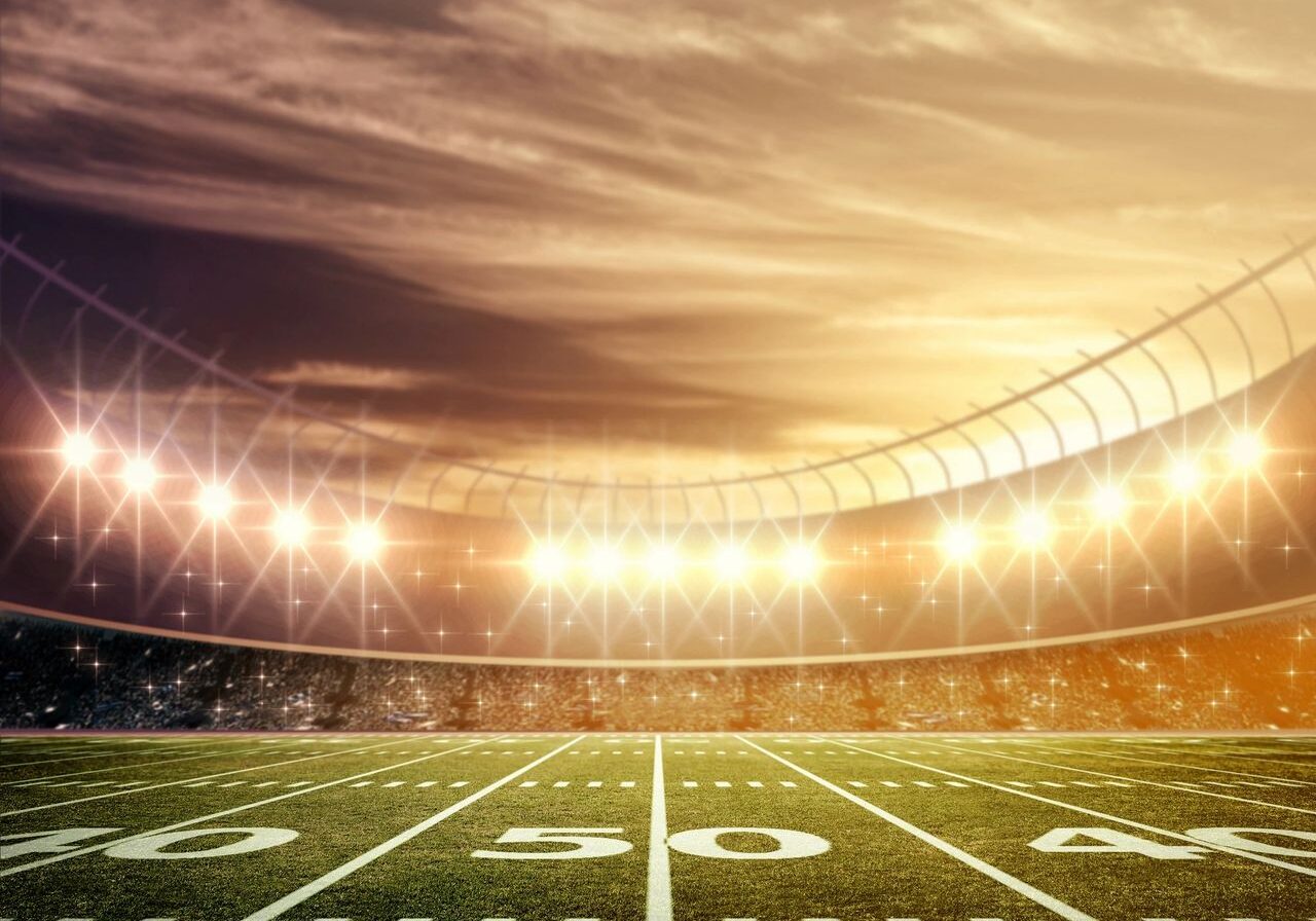 A brightly lit football stadium at sunset.